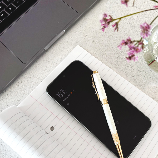 A phone, notepad and laptop on a desk